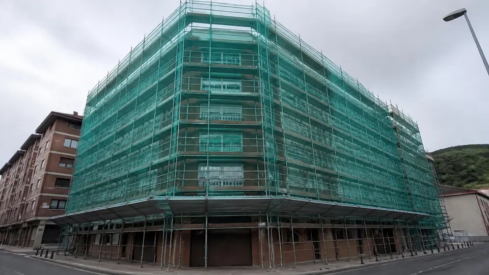 Edificio de viviendas con andamio y malla de seguridad durante una obra de rehabilitación de fachada