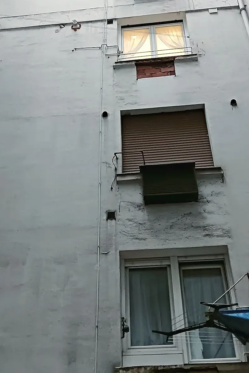 Fachada de patio interior antes de la obra, con revoco manchado y zonas desprendidas, en Estación de Basurto, 12 (Bilbao)